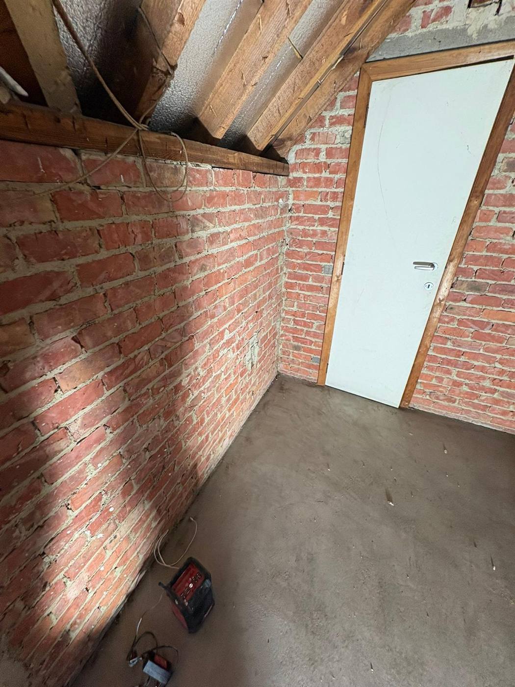 Combles avant travaux : structure en brique apparente et charpente brute